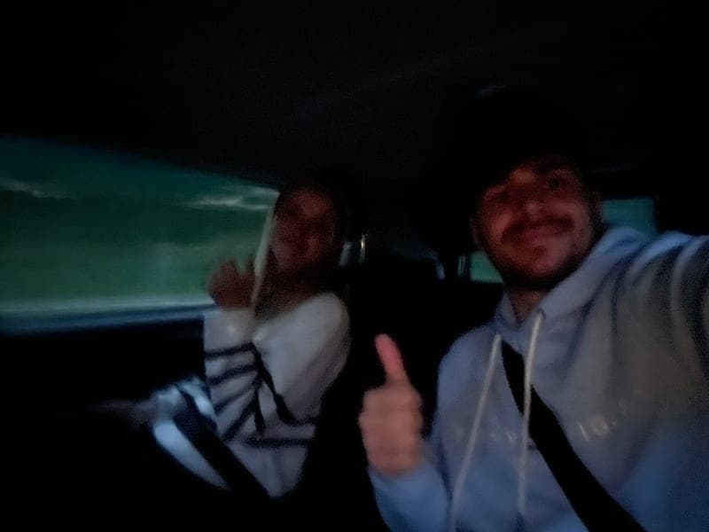 Miriam und Hendrik auf der Rückbank des Taxis, beide zeigen den Daumen nach oben